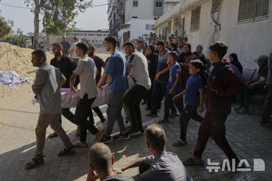[가자시티=AP/뉴시스] 6월 11일 가자지구 가자시티 알시파 병원 인근에서 팔레스타인 주민들이 전날 밤 구호품을 받으려다 총격으로 숨진 사람의 시신을 옮기고 있다.  미국과 이스라엘이 마련한 가자 인도주의재단(GHF) 구호품을 받으려 필사적으로 접근하던 팔레스타인 난민들은 이스라엘군(IDF)의 총격을 받아 36명이 숨지고 207명이 부상했다. 2025.06.13.