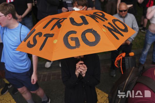 [워싱턴=AP/뉴시스] 미국 워싱턴에서 육군 창설 250주년 기념 대규모 열병식이 열린 가운데 일부 시위 참가자들이 트럼프 반대 문구가 새겨진 우산을 들고 나왔다. 2025.06.15.