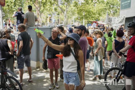 [바르셀로나=AP/뉴시스] 15일(현지 시간) 스페인 바르셀로나에서 오버투어리즘(과잉 관광)에 항의하는 시위가 열린 가운데 한 참가자가 물총을 쏘고 있다. 2025.06.16.