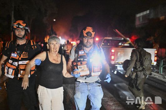 [하이파=AP/뉴시스] 15일(현지 시간) 이스라엘 북부 하이파에서 소구조대원들이 이란의 미사일 공격으로 부상한 여성을 대피시키고 있다. 2025.06.16.