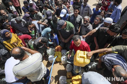 [가자시티=신화/뉴시스] 지난 16일(현지 시간) 전쟁으로 물 부족 사태가 이어지고 있는 가자지구 가자시티 천막촌 인근에서 팔레스타인 피란민들이 식수를 받고 있다. 2025.06.24.