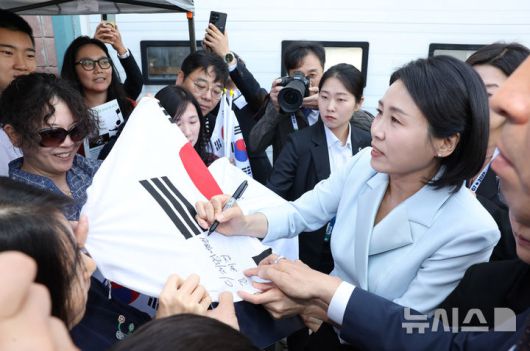 [캘거리=뉴시스] 최진석 기자 = 이재명 대통령 부인 김혜경 여사가 17일(현지 시간) 캐나다 앨버타주 캘거리 한인회관에서 열린 캐나다 서부 동포사회와의 대화를 나누기 전 동포들과 인사를 나누며 태극기에 싸인하고 있다. 2025.06.18. myjs@newsis.com