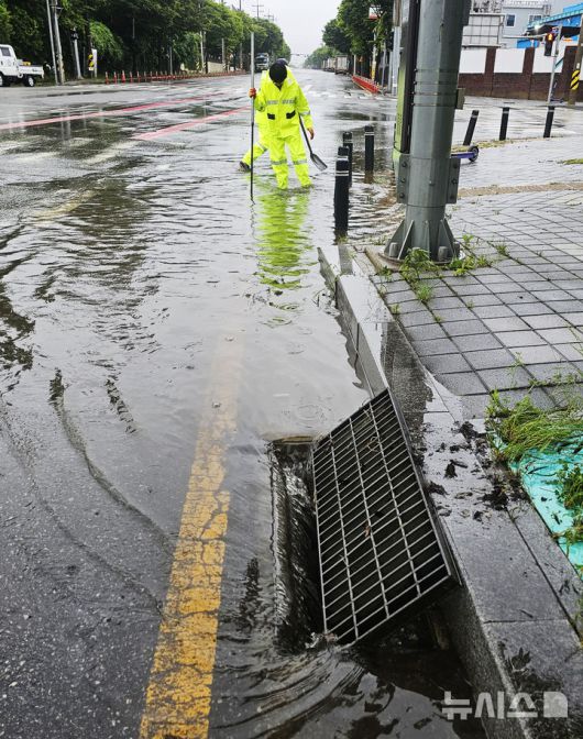 [광주=뉴시스] 박기웅 기자 = 장맛비가 내린 21일 광주 광산구 산월동 한 도로에서 광산구 직원들이 막힌 배수구를 뚫고 있다. (사진 = 광주 광산구 제공) 2025.06.21. photo@newsis.com *재판매 및 DB 금지
