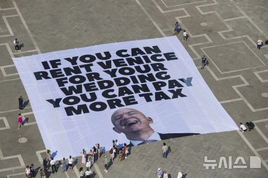 [베니스=AP/뉴시스] 지난 23일(현지 시간) 그린피스가 공개한 사진에 이탈리아 베니스 산 마르코 광장에서 아마존 창립자 제프 베이조스의 결혼식을 반대하는 현수막이 펼쳐져 있다. 2025.06.26.