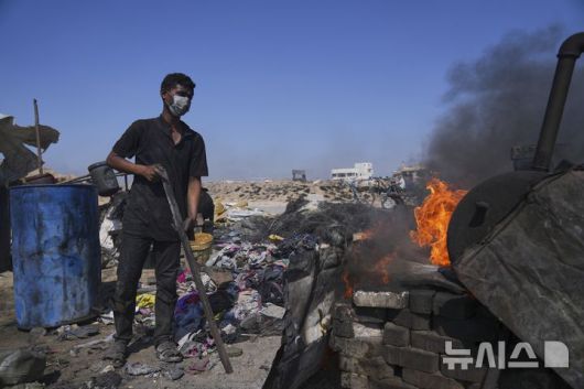 [가자시티=AP/뉴시스] 지난 22일(현지 시간) 가자지구 가자시티 남쪽 시로드에서 모하메드 나짐이라는 팔레스타인 청년이 플라스틱을 녹여 연료를 추출하기 위한 버너를 준비하고 있다. 팔레스타인 청년들은 플라스틱 폐기물을 금속 드럼에 넣고 가열해 만든 연료를 병에 담아 판매하며, 이는 현지에서 발전기나 이동용 연료로 사용된다. 유독한 연기와 불길에 노출되는 고된 작업이지만, 이들에게는 가족의 생계를 이어가는 거의 유일한 수단이다. 2025.06.25.