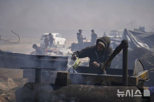 [가자시티=AP/뉴시스] 지난 22일(현지 시간) 가자지구 가자시티 남쪽 시로드에서 팔레스타인인이 플라스틱에서 추출한 연료를 식히기 위해 물을 사용하고 있다. 팔레스타인 청년들은 플라스틱 폐기물을 금속 드럼에 넣고 가열해 만든 연료를 병에 담아 판매하며, 이는 현지에서 발전기나 이동용 연료로 사용된다. 유독한 연기와 불길에 노출되는 고된 작업이지만, 이들에게는 가족의 생계를 이어가는 거의 유일한 수단이다. 2025.06.25.