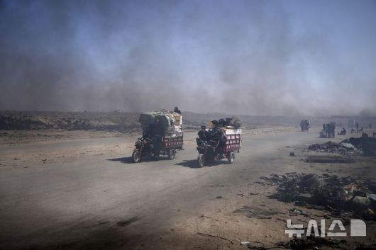 [가자시티=AP/뉴시스] 지난 22일(현지 시간) 가자지구 가자시티 남쪽 시로드에서 팔레스타인 주민들이 플라스틱을 녹여 연료를 추출하는 임시 버너에서 뿜어져 나오는 검은 연기 속을 지나가고 있다. 팔레스타인 청년들은 플라스틱 폐기물을 금속 드럼에 넣고 가열해 만든 연료를 병에 담아 판매하며, 이는 현지에서 발전기나 이동용 연료로 사용된다. 유독한 연기와 불길에 노출되는 고된 작업이지만, 이들에게는 가족의 생계를 이어가는 거의 유일한 수단이다. 2025.06.25.