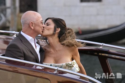 [베네치아=AP/뉴시스] 아마존 창업자 제프 베이조스와 약혼녀 로렌 산체스가 26일(현지 시간) 결혼식 전 열리는 리셉션에 참석하기 위해 이탈리아 베네치아 아만 베니스 호텔을 나서며 입을 맞추고 있다. 2025.06.27.