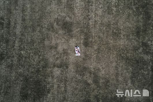 [프랑크푸르트=AP/뉴시스] 1일(현지 시간) 독일 프랑크푸르트 한 공원에서 한 여성이 무더운 날씨 속 메마른 풀밭에 누워 일광욕을 하고 있다. 2025.07.02.