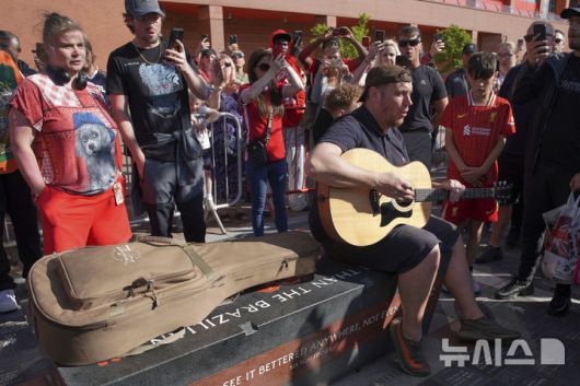 [리버풀=AP/뉴시스] 3일(현지 시간) 잉글랜드 프리미어리그(EPL) 리버풀의 홈구장인 안필드 스타디움에서 한 남성이 이날 새벽 교통사고로 숨진 공격수 디오구 조타(28)을 추모하면서 구단 응원가 YNWA(You'll Never Walk Alone)를 연주하고 있다. 조타는 동생 안드레 시우바와 함께 차량으로 이동하던 중 스페인 사모라 인근에서 사고로 목숨을 잃었다. 2025.07.04.