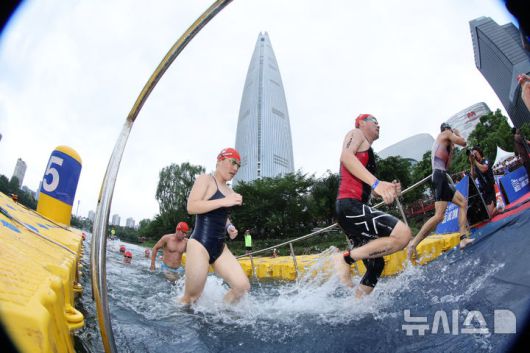 [서울=뉴시스] 김근수 기자 = 6일 오전 서울 송파구 롯데월드타워 일대에서 열린 '2025 롯데 아쿠아슬론'에서 참가자들이 수영을 마치고 이동하고 있다. 철인 3종 경기에서 사이클론을 제외한 오픈워터 수영과 마라톤을 함께 겨루는 '2024 롯데 아쿠아슬론'은 석촌호수 두 바퀴(총 1.5Km)를 완영 후, 롯데월드타워 1층부터 123층까지 2,917개의 계단을 오르는 수직 마라톤 스카이런(SKY RUN)으로 진행됐다.(공동취재) 2025.07.06. photo@newsis.com
