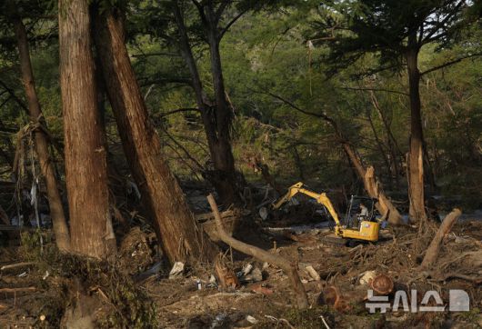 [텍사스=AP/뉴시스] 8일(현지 시간) 미국 텍사스주 과달루페 강 인근 홍수 피해 지역에서 자원봉사자가 굴삭기를 이용해 나뭇가지 등 잔해를 치우고 있다. 2025.07.09.