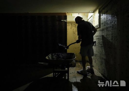 [텍사스=AP/뉴시스] 8일(현지 시간) 미국 텍사스주 잉그램의 홍수 피해 주택에서 주민이 토사를 치우고 있다. 2025.07.09.