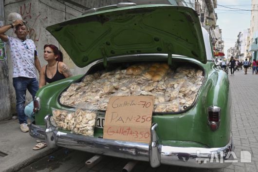 [아바나=AP/뉴시스] 15일(현지 시간) 쿠바 아바나에서 상인들이 미국산 클래식카 트렁크에 수제 감자칩과 빵을 가득 싣고 손님을 기다리고 있다. 2025.07.16.