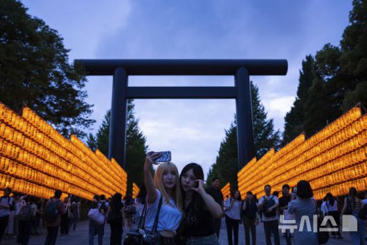 [도쿄=AP/뉴시스] 지난달 16일 일본 도쿄 야스쿠니 신사에서 미타마 마쓰리가 열려 방문객들이 노란색 등불을 배경으로 셀카를 찍고 있다. 2025.08.15.