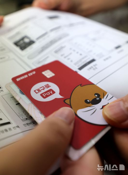 [대구=뉴시스] 이무열 기자 = 민생회복 소비쿠폰 신청 첫 날인 21일 대구 중구 대신동행정복지센터에서 한 시민이 선불카드를 수령받고 있다. 2025.07.21. lmy@newsis.com