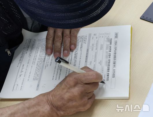 [인천=뉴시스] 전진환 기자 = 민생회복 소비쿠폰 1차 신청 첫 날일 21일 오전 인천 미추홀구 숭의1,3동 행정복지센터에서 한 어르신이 신청서를 작성하고 있다. 2025.07.21. amin2@newsis.com