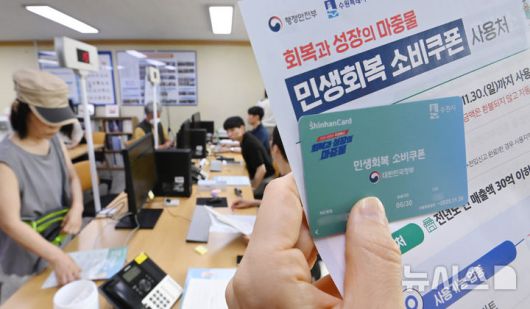 [수원=뉴시스] 김종택 기자 = 정부의 민생회복 소비쿠폰 1차 신청 첫날인 21일 경기 수원시 행궁동 행정복지센터에서 한 시민이 선불카드를 수령받고 있다. 소비쿠폰 신청은 요일제에 따라 출생 연도 끝자리 1·6은 월요일, 2·7은 화요일, 3·8은 수요일, 4·9는 목요일, 5·0은 금요일에 신청할 수 있다. 주말에는 온라인 신청만 가능하며 사용기한은 11월 30일까지다. 2025.07.21. jtk@newsis.com