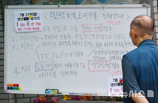 [수원=뉴시스] 김종택 기자 = 정부의 민생회복 소비쿠폰 1차 신청 첫날인 21일 경기 수원시 세류3동 행정복지센터에서 한 시민이 지원금 신청 안내문을 살펴보고 있다. 소비쿠폰 신청은 요일제에 따라 출생 연도 끝자리 1·6은 월요일, 2·7은 화요일, 3·8은 수요일, 4·9는 목요일, 5·0은 금요일에 신청할 수 있다. 주말에는 온라인 신청만 가능하며 사용기한은 11월 30일까지다. 2025.07.21. jtk@newsis.com