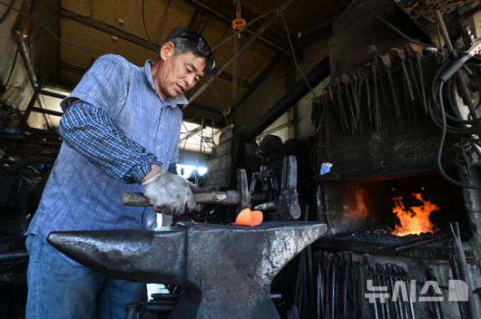 [광주=뉴시스] 이영주 기자 = 광주지역 최고기온이 37도까지 오른 29일 오후 광주 광산구 송정대장간에서 최종호(61) 송정대장간 대표가 망치와 모루를 이용해 약초를 캐는 도구를 만들고 있다. 광주지역에는 지난 20일 이후 현재까지 열흘 동안 폭염특보가 이어지고 있다. 2025.07.29. leeyj2578@newsis.com