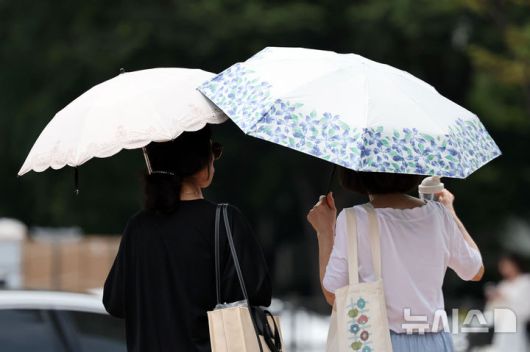 [서울=뉴시스] 조성우 기자 = 서울에 일주일째 폭염경보가 이어지는 30일 서울 시내의 한 거리에서 시민이 양산을 쓰고 이동하고 있다. 2025.07.30. xconfind@newsis.com