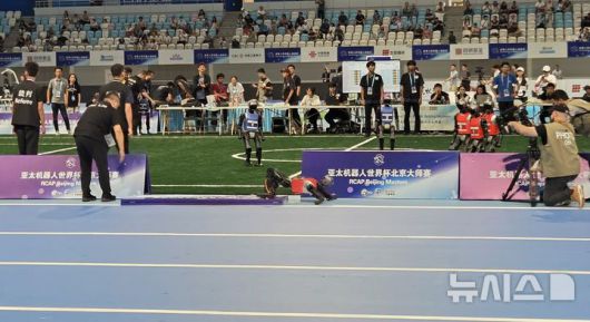 [베이징=뉴시스] 박정규 특파원 = 15일 오전 '2025 세계휴머노이드로봇운동회'가 열린 중국 베이징 국가스피드스케이팅경기장에서 진행된 로봇축구 경기 도중 한 로봇이 펜스를 넘어뜨린 채 쓰러져 있다. 2025.08.15 pjk76@newsis.com