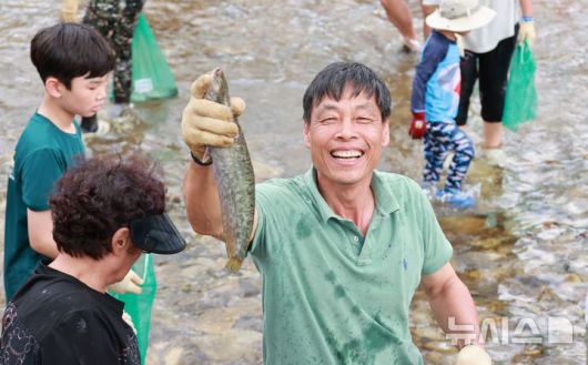 [괴산=뉴시스] 서주영 기자 = 6일 충북 괴산군의 동진천에서 열린 2025 괴산고추축제 프로그램 '고추물고기를 잡아라'의 한 참가자가 잡은 물고기를 들고 웃음을 짓고 있다. (사진= 괴산군 제공) 2025.09.06. photo@newsis.com