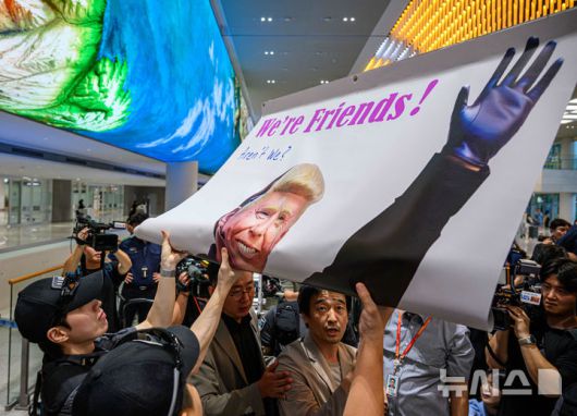 [인천공항=뉴시스] 황준선 기자 = 미국 조지아주 이민세관단속국(ICE) 구금 시설에서 구금됐다 풀려난 한국인들이 탑승한 전세기가 지난 12일 인천국제공항 2터미널에 도착한 가운데, 이제석 이제석광고연구소 대표가 입국장에서 트럼프 대통령 얼굴이 담긴 플래카드 퍼포먼스를 펼치고 있다. (공동취재) 2025.09.15. photo@newsis.com