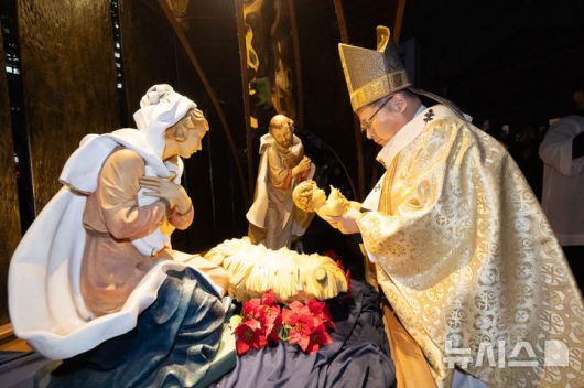 [서울=뉴시스] 황준선 기자  = 천주교 서울대교구장 정순택 대주교가 성탄절인 25일 서울 중구 명동대성당 앞마당에서 주님 성탄 대축일 밤 미사를 앞두고 아기 예수를 말 구유에 안치하는 '구유 예절' 의식을 하고 있다. 2025.12.25. hwang@newsis.com