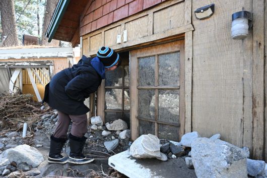 [라이트우드=AP/뉴시스] 25일(현지 시간) 미 캘리포니아주 라이트우드에서 한 주민이 연이은 폭풍우로 침수됐다가 흙더미에 파묻힌 채 남아 있는 집을 살펴보고 있다. 캘리포니아에 대규모의 '대기의 강' 현상이 나타나 곳곳에 폭풍우와 뇌우 등으로 돌발 홍수가 발생하는 등 피해가 잇따랐다. 개빈 뉴섬 캘리포니아 주지사는 일부 지역에 비상사태를 선포했다. 2025.12.26.