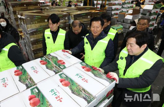 [서울=뉴시스] 조성우 기자 = 정청래(왼쪽 세 번째) 더불어민주당 대표가 7일 오전 서울 송파구 가락동 농수산물 종합도매시장 중앙청과에서 경매를 마친 사과 상자를 운반차에 싣고 있다. 2026.01.07. xconfind@newsis.com