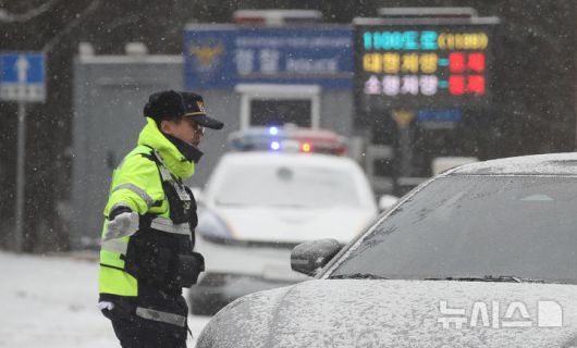 [제주=뉴시스] 우장호 기자 = 제주 산지·중산간·동부·남부에 대설특보가 내려진 11일 오전 제주시 어승생 삼거리 입구에서 제주서부경찰서 소속 경찰관이 도로통제를 하고 있다. 기상청에 따르면 제주도는 12일까지 한라산 등 고지대를 중심으로 최대 15㎝의 눈이 내려 쌓일 것으로 예측됐다. 2026.01.11. woo1223@newsis.com