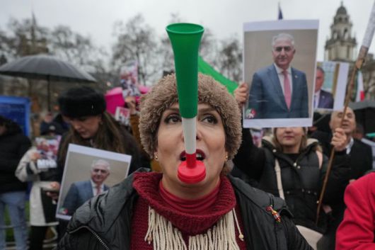[런던=AP/뉴시스] 13일(현지 시간) 영국 런던 의회 건물 앞에서 시위대가 미국에 망명 중인 레자 팔라비 이란 왕세자 사진을 들고 이란 반정부 시위대에 연대하는 시위를 벌이고 있다. 2026.01.14.
