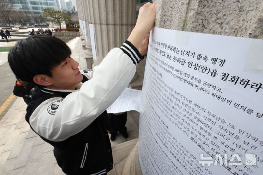 [서울=뉴시스] 황준선 기자 = 한국외대 총학생회 소속 학생들이 19일 오후 서울 동대문구 한국외국어대학교에서 학교측의 등록금 인상 계획을 규탄하는 대자보를 붙이고 있다. 2026.01.19. hwang@newsis.com