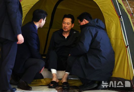 [서울=뉴시스] 김명년 기자 = 통일교·공천헌금 '쌍특검' 수용을 촉구하며 여드레째 단식중인 장동혁 국민의힘 대표가 21일 서울 여의도 국회 로텐더홀 농성장 텐트에서 일어나 당직자와 대화하고 있다. 2026.01.22. kmn@newsis.com