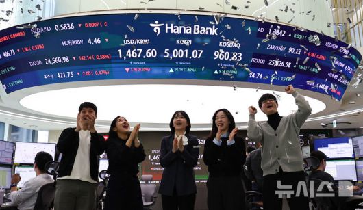 [서울=뉴시스] 최진석 기자 = 코스피가 꿈의 숫자로 여겨지던 '오천피'에 도달하며 코스피 5000 시대가 열린 22일 오전 서울 중구 하나은행 딜링룸에서 관계자들이 코스피 5000 돌파를 축하하고 있다. 코스피는 전 거래일(4909.93)보다 77.13포인트(1.57%) 상승한 4987.06에 개장했다.2026.01.22. myjs@newsis.com