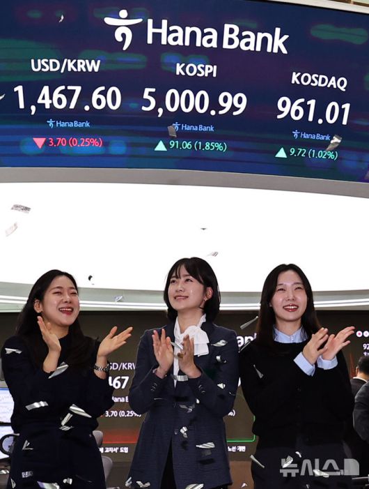 [서울=뉴시스] 최진석 기자 = 코스피가 꿈의 숫자로 여겨지던 '오천피'에 도달하며 코스피 5000 시대가 열린 22일 오전 서울 중구 하나은행 딜링룸에서 관계자들이 코스피 5000 돌파를 축하하고 있다. 코스피는 전 거래일(4909.93)보다 77.13포인트(1.57%) 상승한 4987.06에 개장했다.2026.01.22. myjs@newsis.com