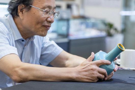 Chen Ketao, executive vice president of the Shanghai Collectors Association, examines a Ru ware celadon-glazed vase with a gilt rim from the Northern Song period. Economic Daily Park Myung-seob