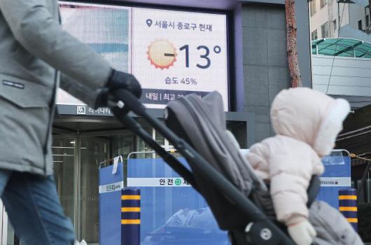 A person pushing a stroller passes by a display showing -13°C (8.6 degrees Fahrenheit) at near Jonggak station in Seoul, Dec. 26, 2025. AJP Han Jun-gu