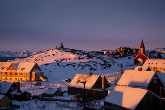 A statue of Hans Egede, a Dano-Norwegian Lutheran missionary, is pictured next to the Cathedral (R) on the top of a hill covered by snow at sunset light in Nuuk, Greenland, on Jan. 21, 2026. AFP-Yonhap