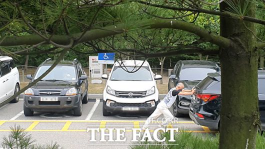 지난달 17일 인천지방법원 후문주차장 장애인 주차구역에서 한 장애인 운전자가 이중 주차된 차량을 직접 밀고 있다. 이러한 배려없는 불법주차로 인해 장애인 운전자들은 고통받고 있다./인천지방법원=남윤호 기자