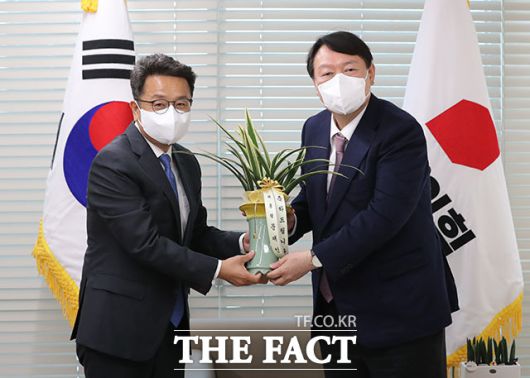 윤석열 국민의힘 대선 후보(오른쪽)가 지난 15일 서울 여의도 중앙당사에서 이철희 청와대 정무수석으로부터 문재인 대통령의 '축하 난'을 전달받고 있는 모습. /남윤호 기자