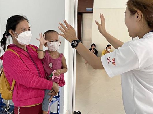 '베트남 얼굴 기형 어린이 무료 수술' 행사에 참여한 SK 대학생 자원봉사단이 수술한 어린이, 가족과 인사하고 있다. /SK그룹