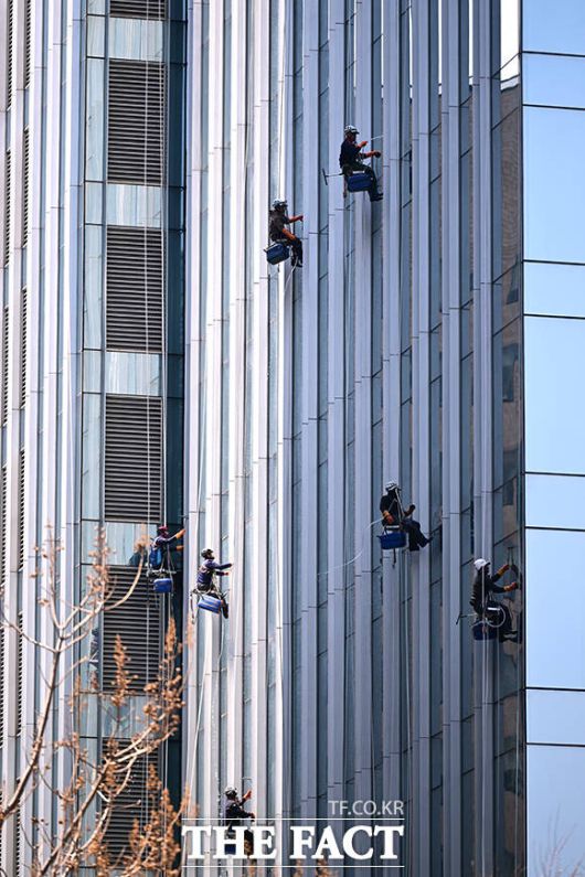 빌딩숲 속 외벽 청소하는 작업자들.