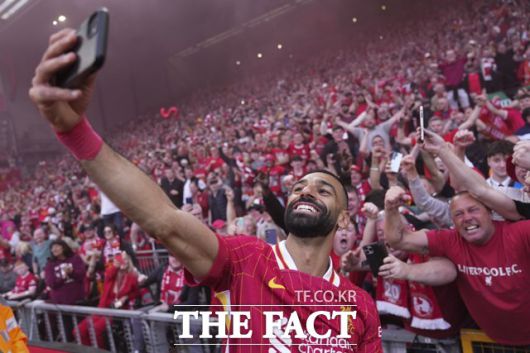 리버풀 우승의 '일등공신' 모하메드 살라가 28일 토트넘과 2024~2025 EPL 34라운드 홈 경기에서 후반 18분 추가골을 넣은 뒤 팬의 휴대폰으로 셀카를 찍는 세리머니를 펼치고 있다./리버풀=AP.뉴시스