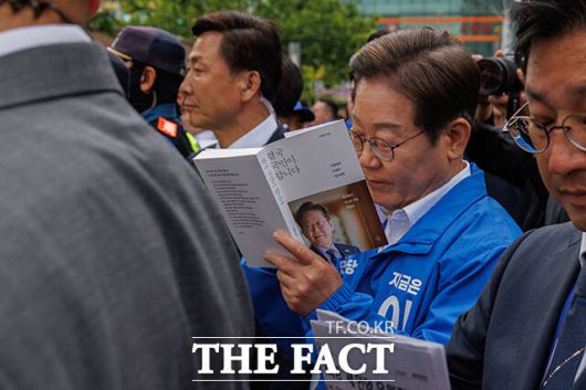 연설현장 떠나며 본인의 저서인 <결국 국민이 이깁니다>에 사인하는 이재명 후보.