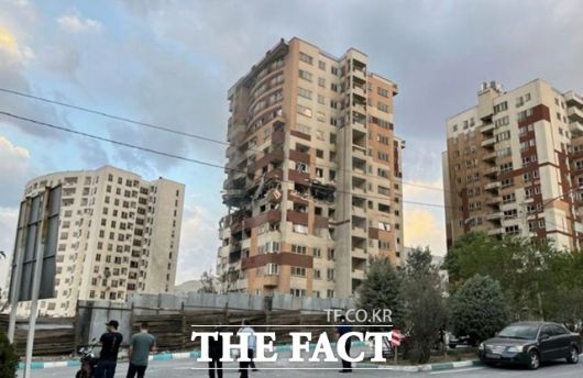 13일(현지시간) 이란 테헤란에서 주민들이 이스라엘의 공습으로 파손된 아파트 건물을 지켜보고 있다. /AP·뉴시스