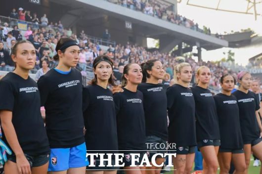 미국 여자프로축구 리그(NWSL) 앤젤시티FC 선수들이 노스캐롤라이나 커리지FC와 경기에 앞서 '이민자 도시 축구단(Immigrant City Football Club)'이라는 문구의 검은색 티셔츠를 입고 트럼프 정부의 이민자 정책에 반대하는 의사를 표시하고 있다./앤젤시티FC