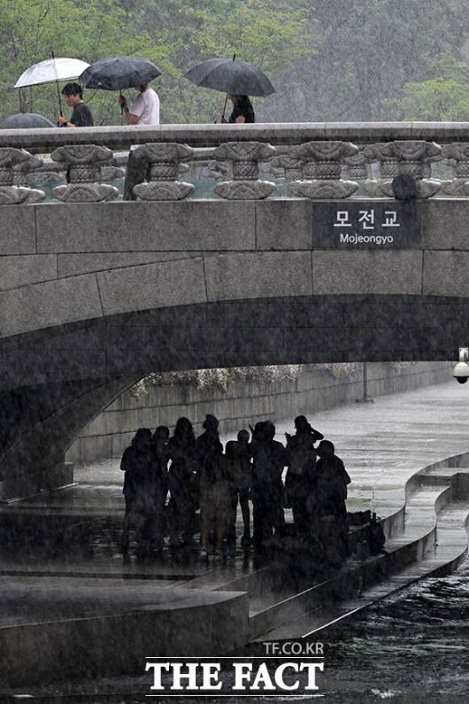 모전교를 사이에 두고 우산쓰고 이동하는 시민들(위)과 비를 피하는 시민들.