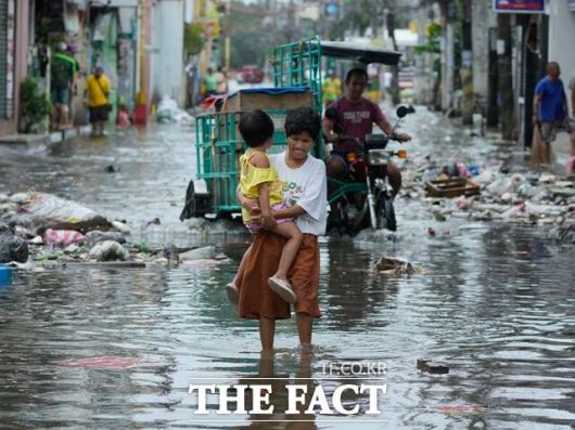 최근 제25호 태풍 '갈매기'가 덮쳐 220명이 넘게 숨진 필리핀에 또 다른 슈퍼태풍 '풍웡'이 덮쳐 2명이 사망하고 약 140만 명 이상이 대피했다. 사진은 10일(현지시간) 필리핀 수도 마닐라시 북서쪽 해안 도시 나보타스에서 침수된 거리를 걷고 있는 이재민의 모습. /AP.뉴시스